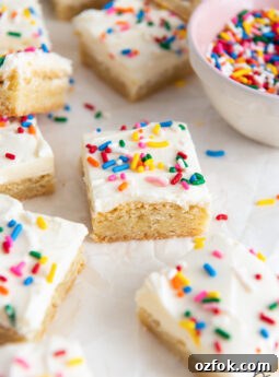 sugar cookie bars with frosting and rainbow sprinkles next to more bars