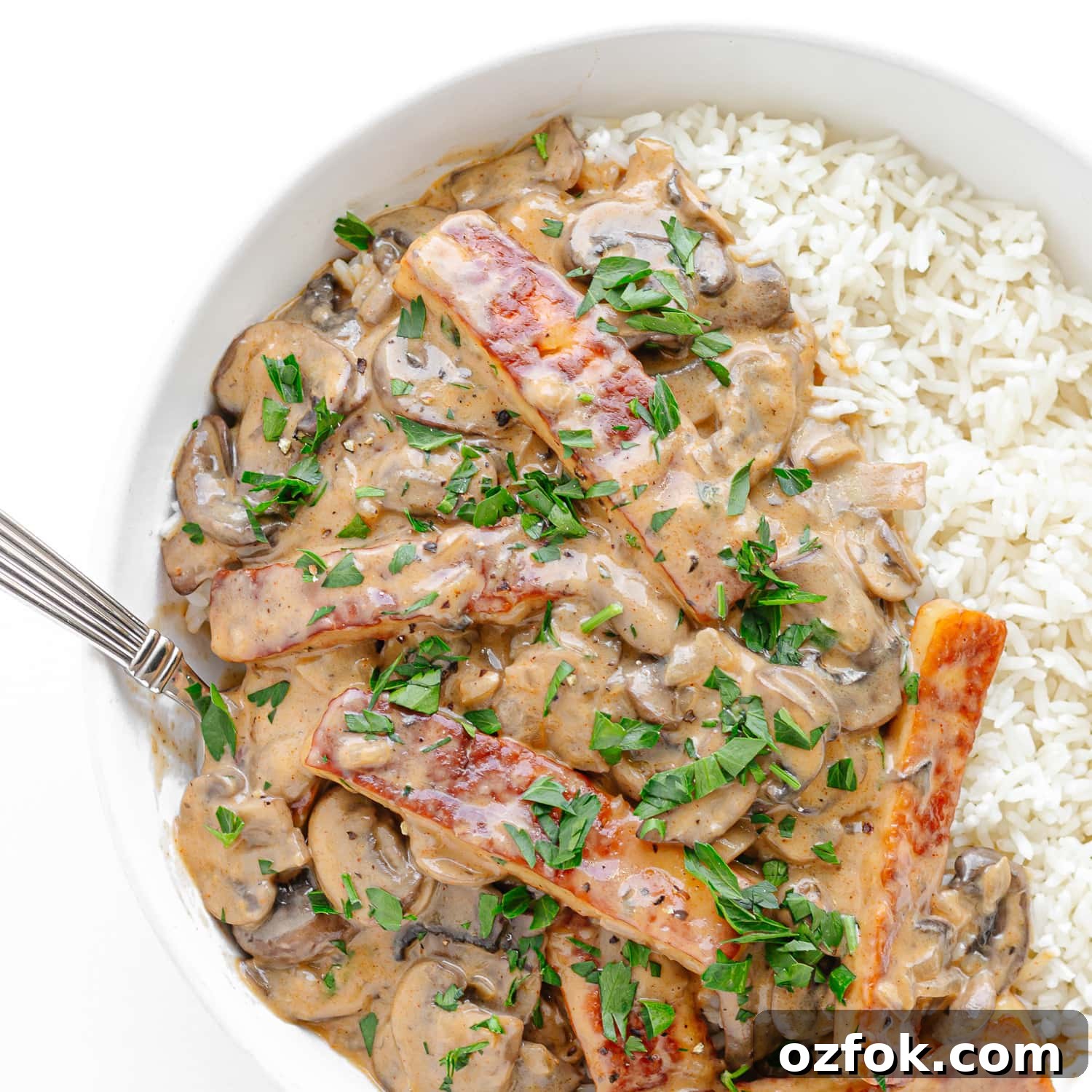 Creamy Halloumi Stroganoff with Mushrooms and Thyme 10 Halloumi Stroganoff served over rice in a white bowl.