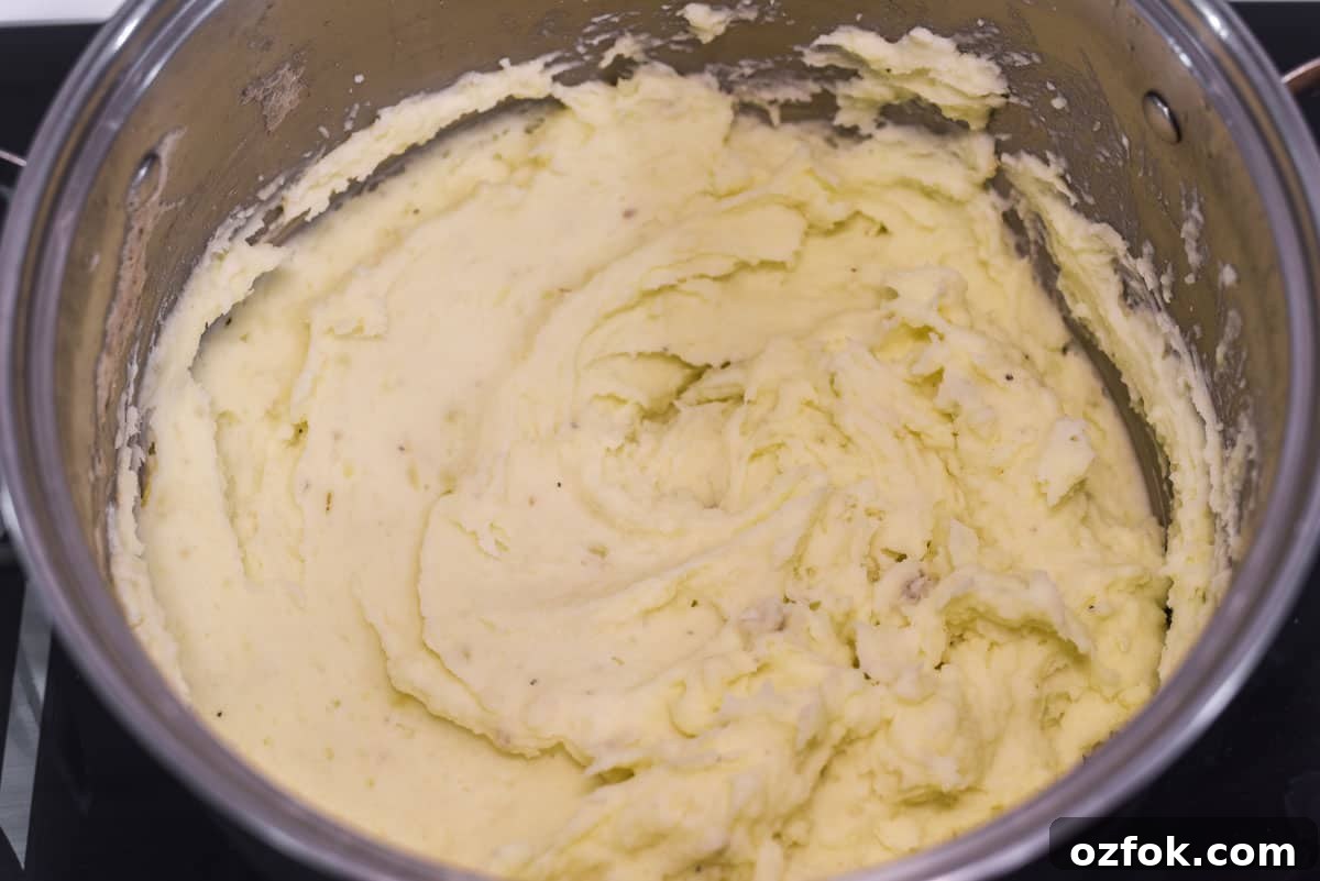 Whipping the mashed potatoes until light and fluffy in large stock pot.