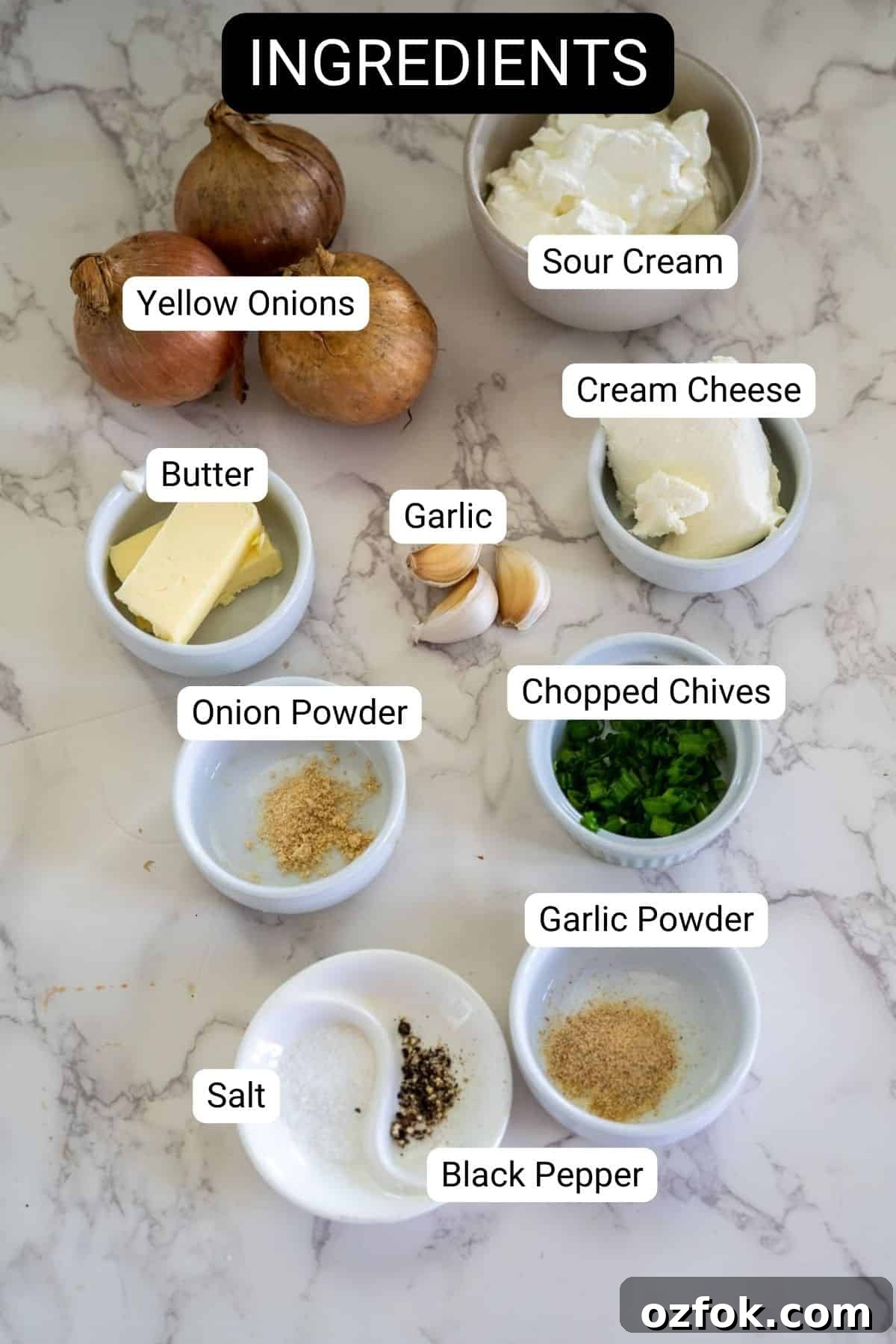 Keto French Onion Dip Recipe for Low-Carb Snacking 3 Labeled ingredients on a marble surface: yellow onions, sour cream, cream cheese, butter, garlic, onion powder, chopped chives, garlic powder, salt, and black pepper.