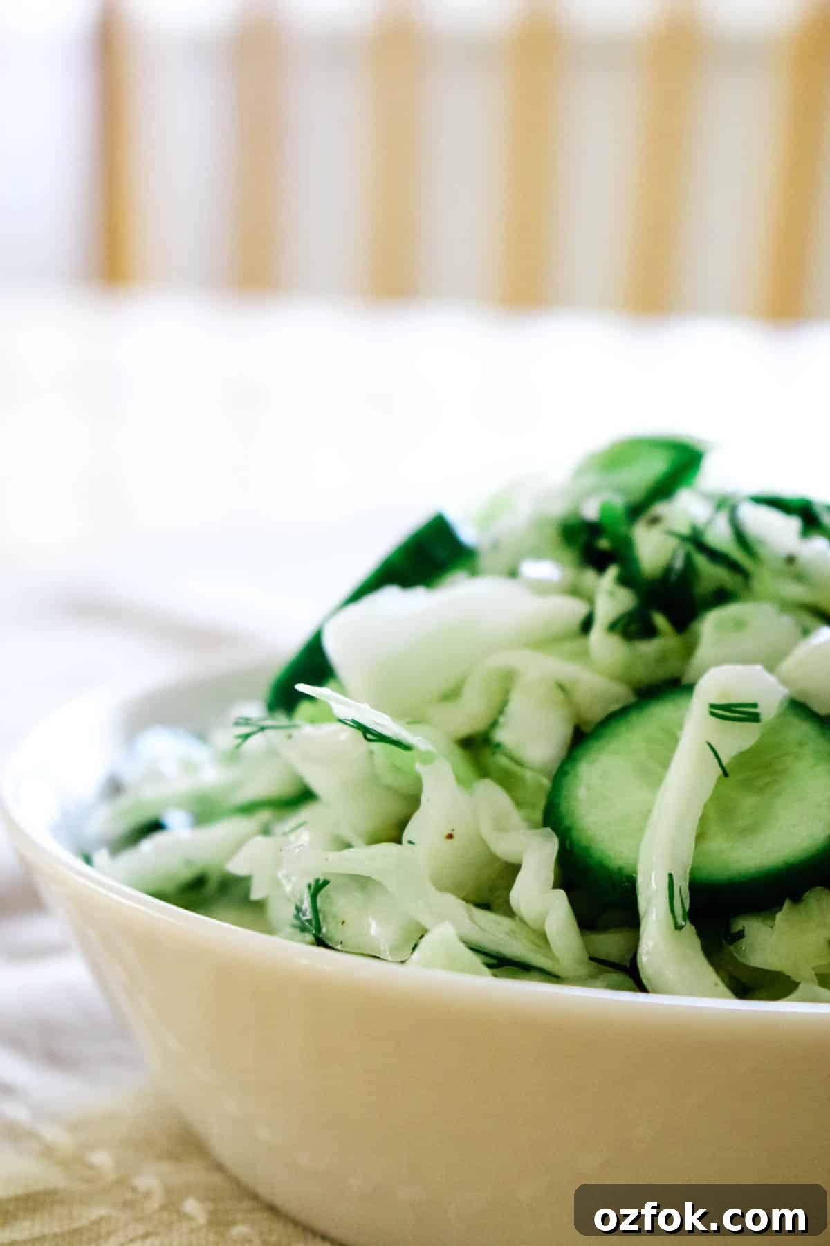 Sliced cucumbers, shredded cabbage in a white bowl