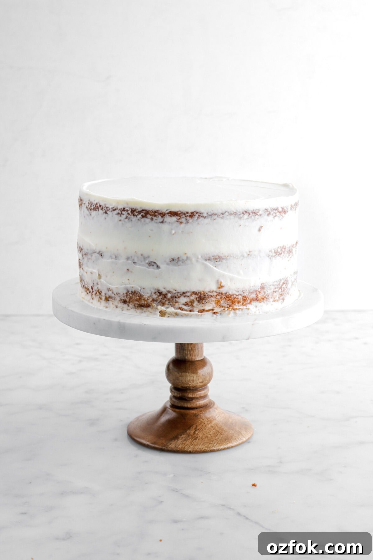 cake with crumb coat on marble cake stand.