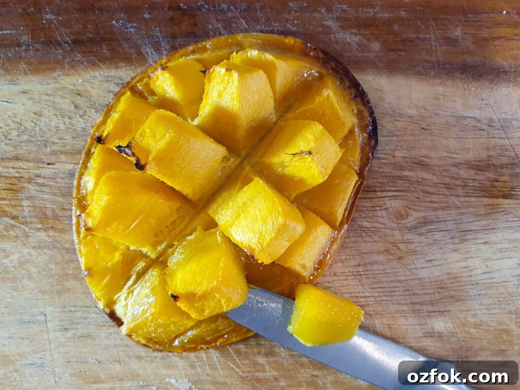 Creamy Mango Ice Cream Recipe: Fresh Mango Frozen Dessert 6 Cutting cooked mango flesh off the mango skin.