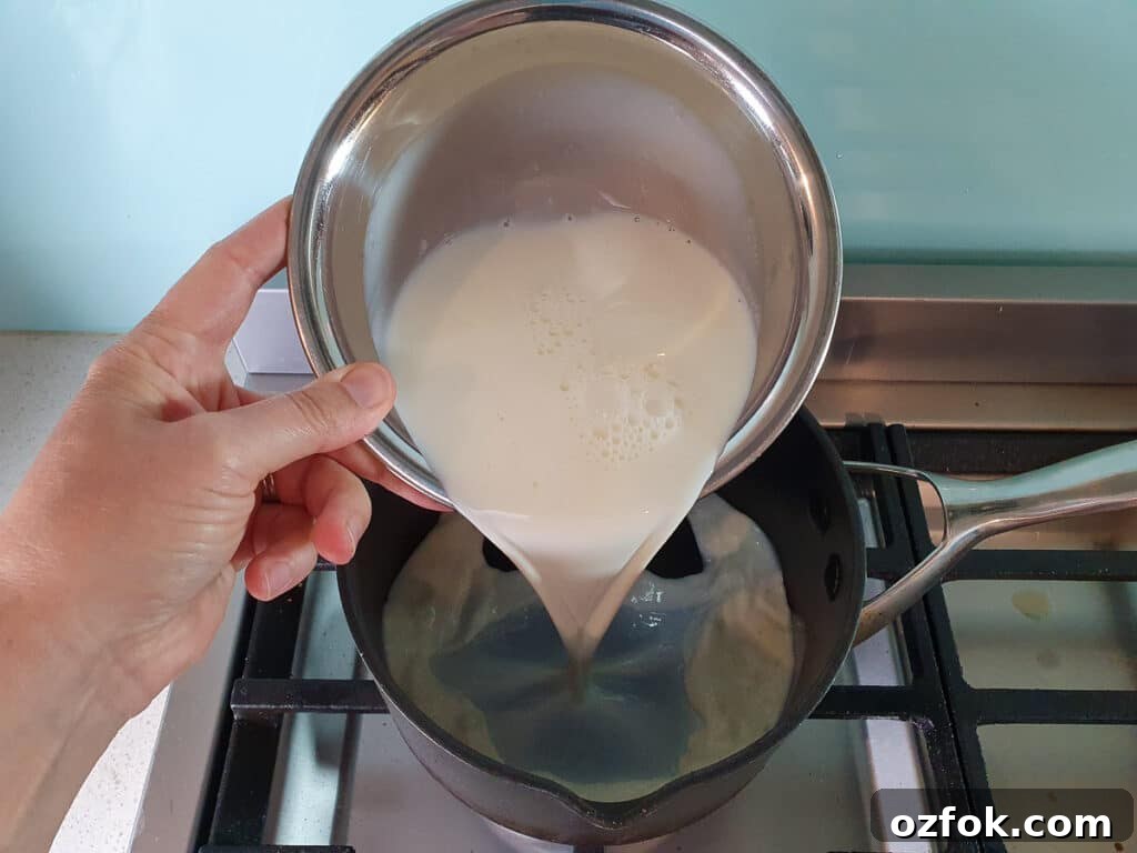 Creamy Mango Ice Cream Recipe: Fresh Mango Frozen Dessert 8 adding milk to pot on stove.