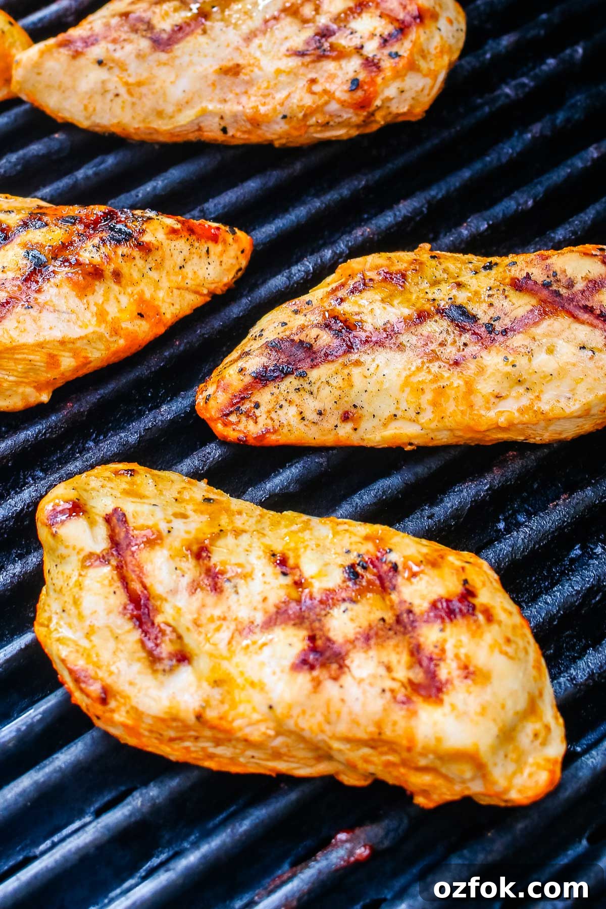 Grilled Buffalo Chicken Breasts with Tangy Blue Cheese Dip 8 Buffalo chicken breasts cooking on outdoor grill grates with visible char marks.