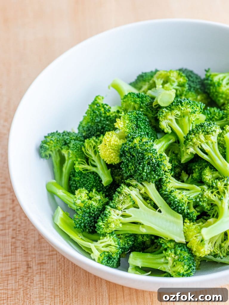 Spicy Korean Radish Salad (Musaengchae) — Authentic Recipe 9 a white bowl with blanched broccoli on a wooden surface