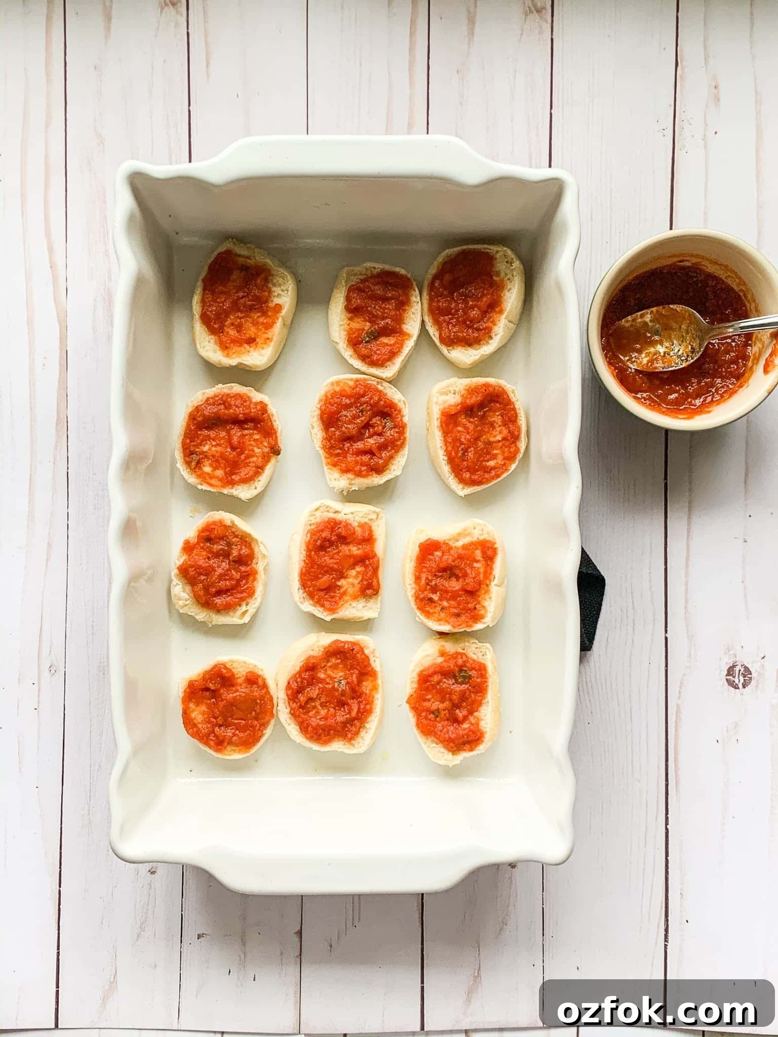 Italian Slider Recipes: Flavorful Mini Sandwiches for Entertaining 5 spreading marinara sauce on mini slider buns inside a baking dish.
