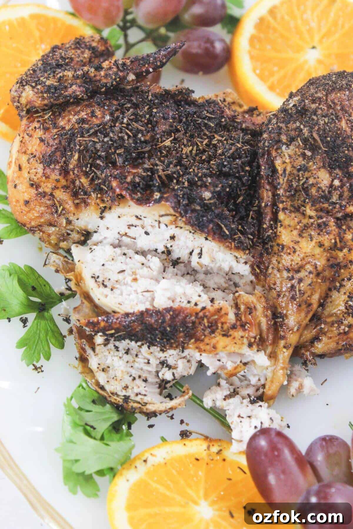 Crispy Air Fryer Spatchcock Chicken Recipe for Juicy Results 12 Roasted chicken with herb seasoning is sliced and served on a platter, garnished with orange slices, parsley, and red grapes.