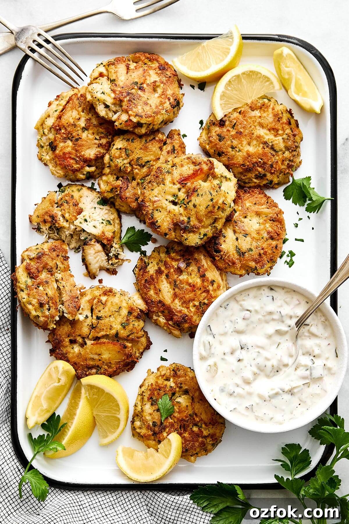 A platter of crab cakes with tartar sauce.