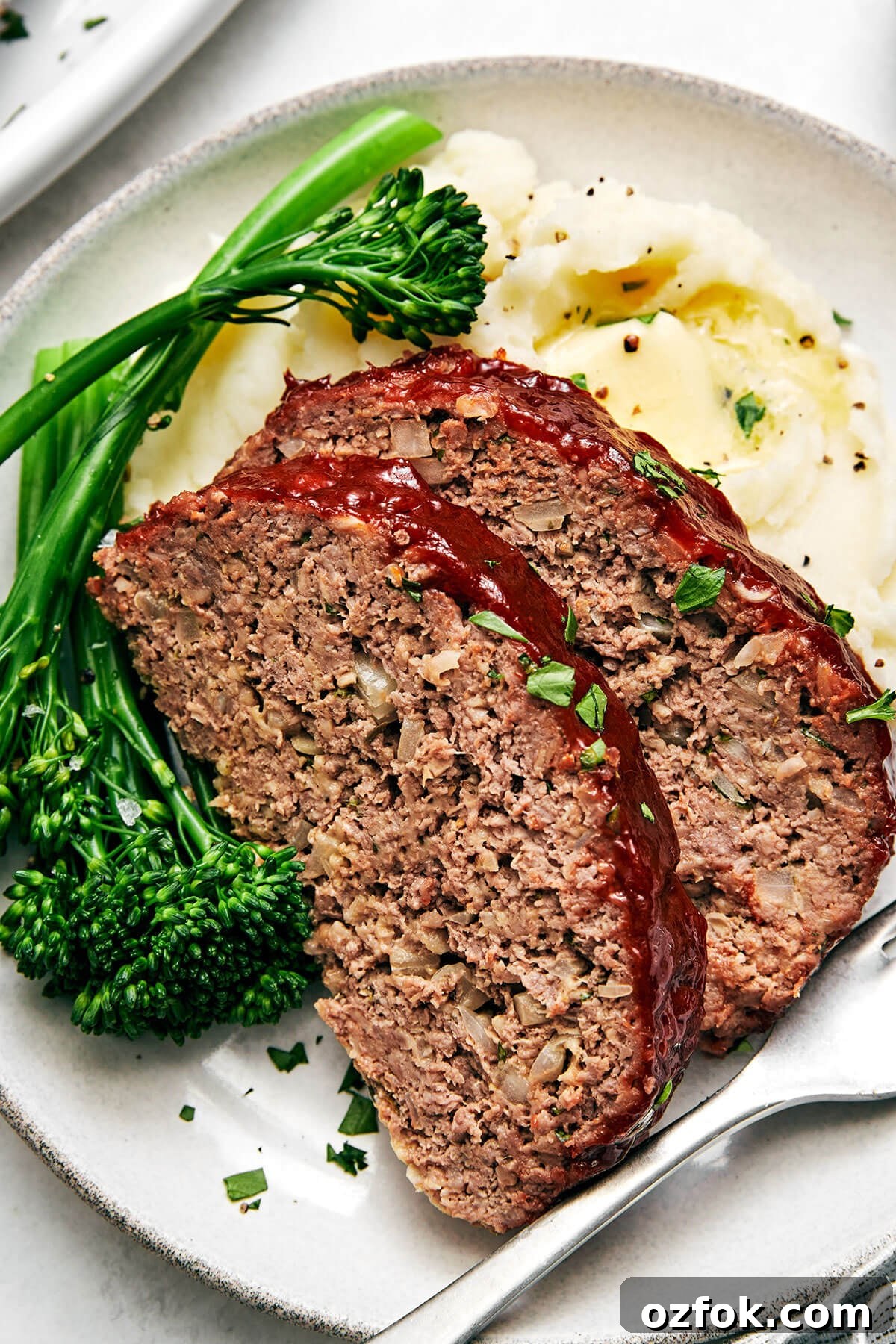 Sliced meatloaf with broccolini and mashed potatoes.