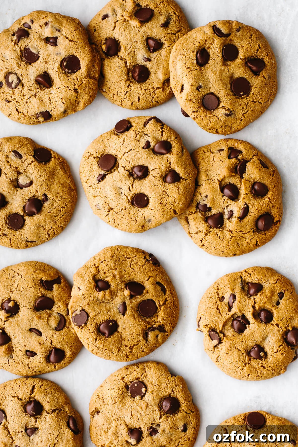 Gluten-free chocolate chip cookies spread out on a baking sheet.