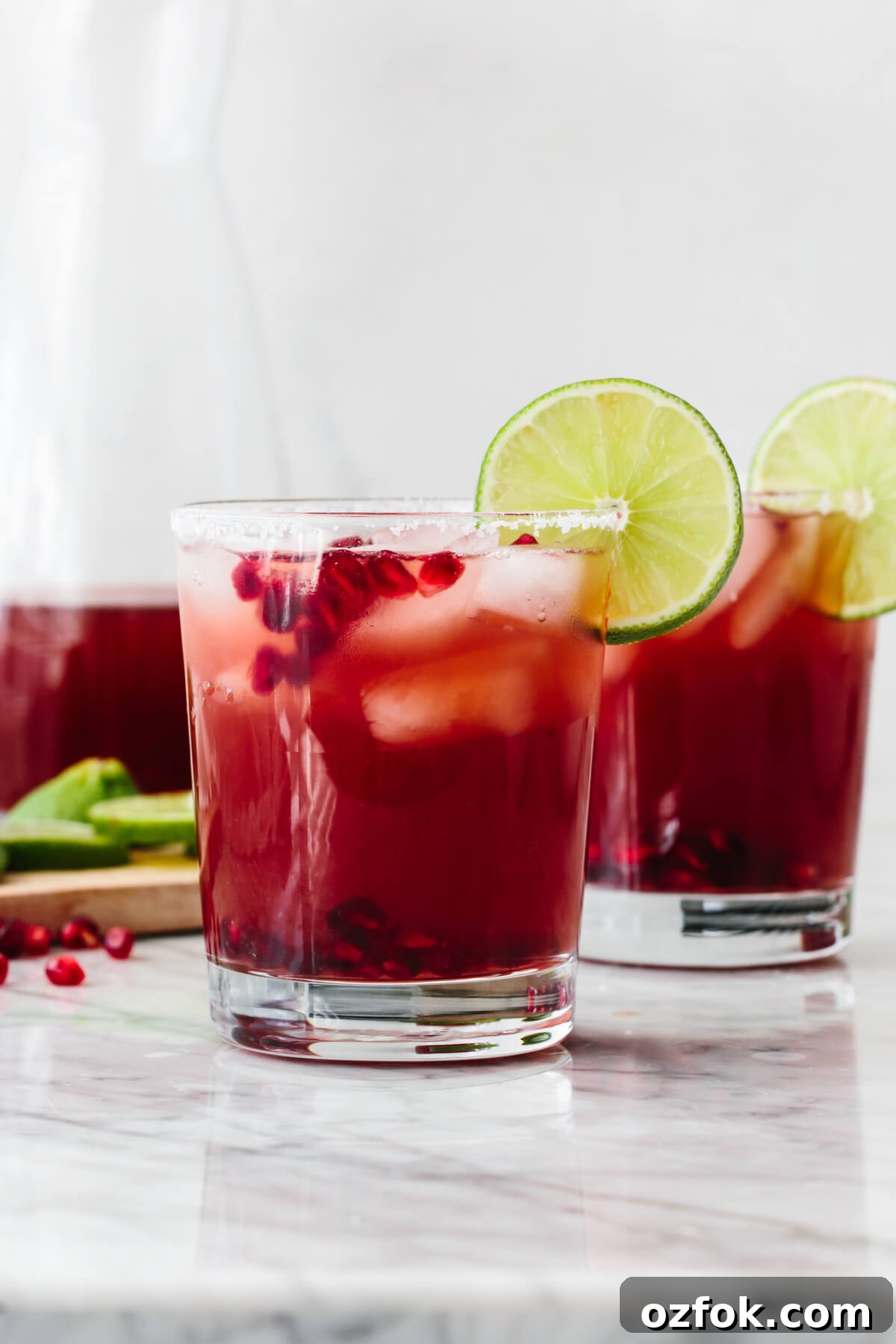 Two glasses of pomegranate margarita on a table.