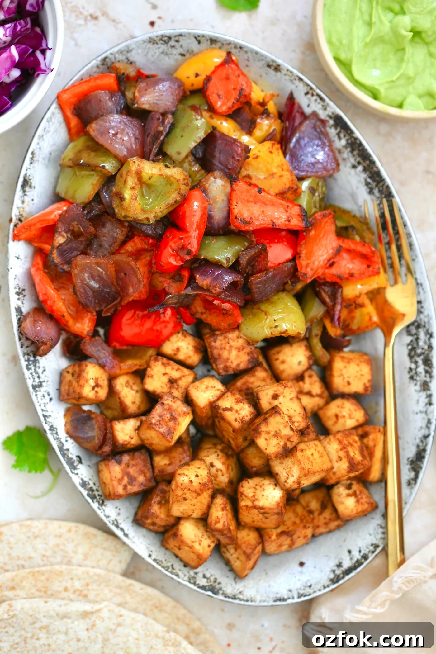 Flavor-Packed Baked Tofu Fajitas with Roasted Veggies 2 silver platter with brown cubes and cooked peppers.