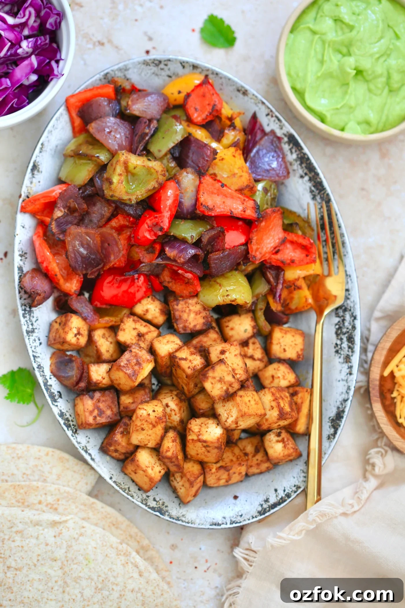 Flavor-Packed Baked Tofu Fajitas with Roasted Veggies 9 plate with brown tofu and colorful peppers.
