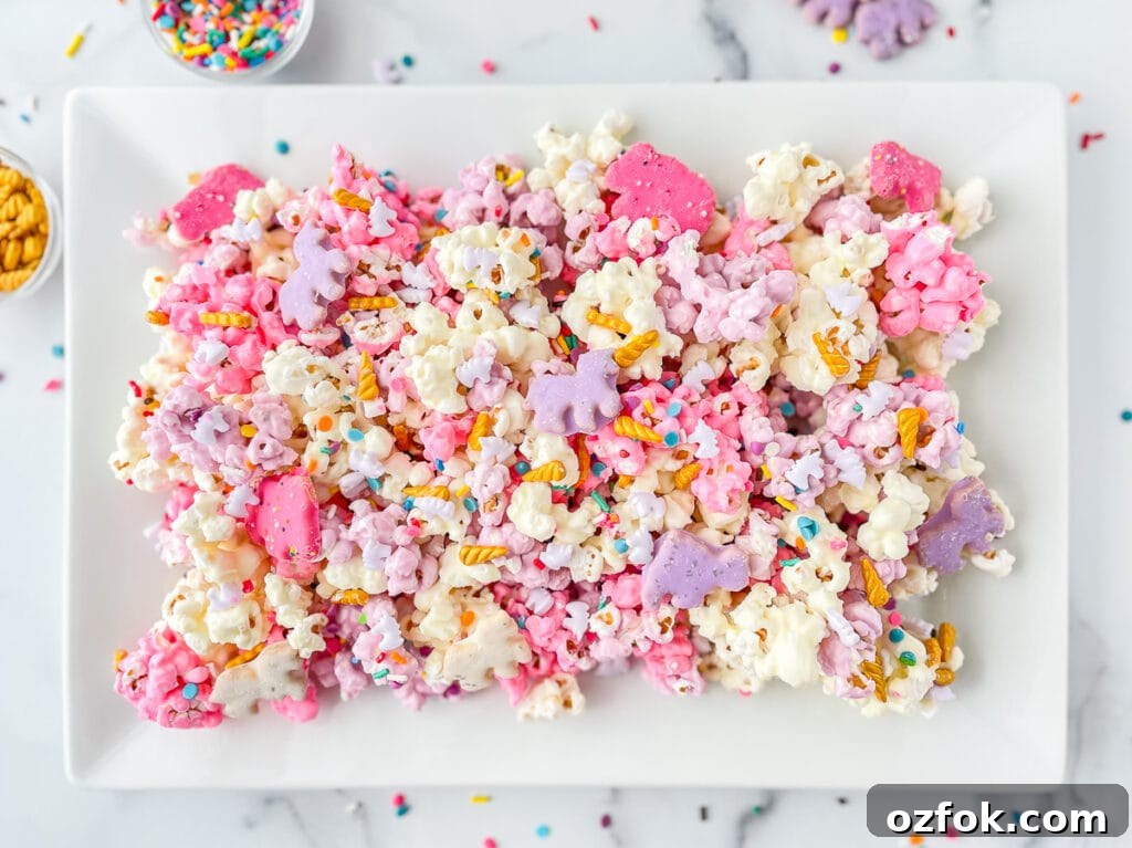 Unicorn Popcorn Recipe for a Magical Party Treat 2 A platter full of pink, white, purple candy coated popcorn, decorated with sprinkles.