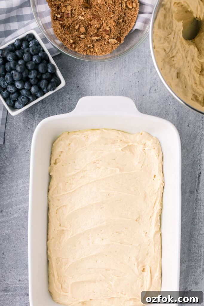 spreading batter over blueberry coffee cake.