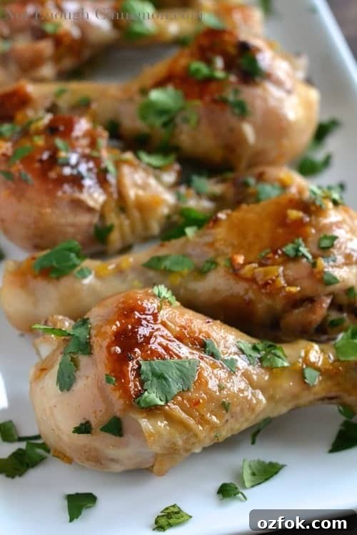 Honey Lemon Ginger Glazed Chicken Drumsticks Recipe 3 Honey Lemon Ginger Glazed Sticky Chicken Drumsticks arranged on a white plate, sprinkled with fresh cilantro