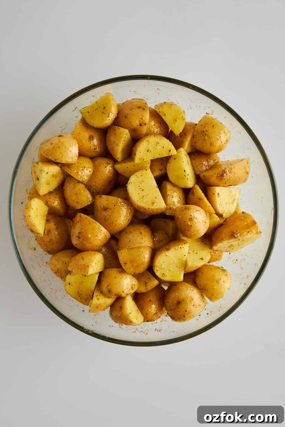 Crispy Air Fryer Greek-Style Lemon Potatoes 3 Seasoned golden potato pieces in a mixing bowl.