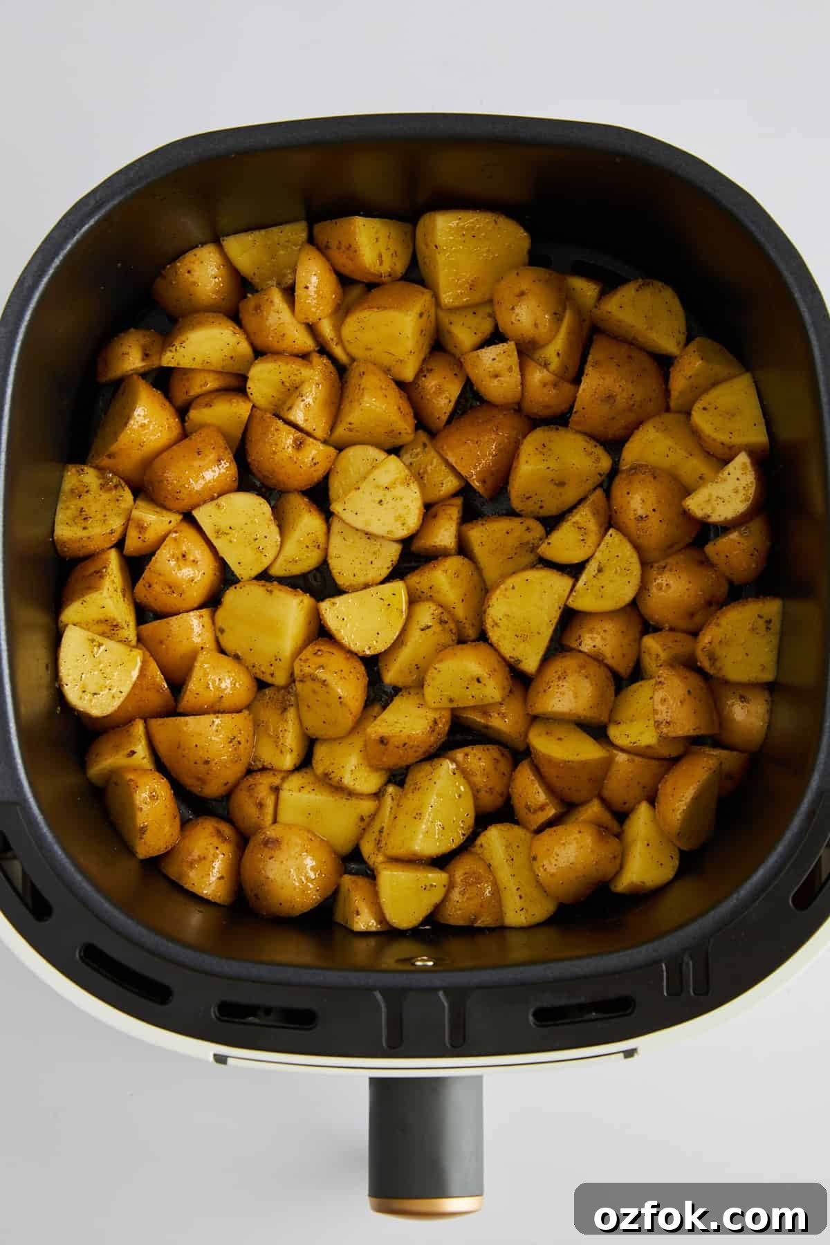 Crispy Air Fryer Greek-Style Lemon Potatoes 4 Uncooked Greek potatoes in an air fryer.