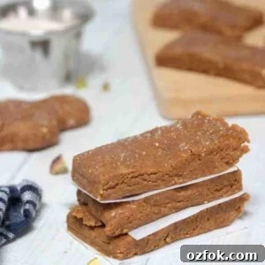 5-Minute Gingerbread Protein Bars Recipe for Quick Snacks 12 Three gingerbread protein bars stacked with parchment paper between them and pistachios around them.