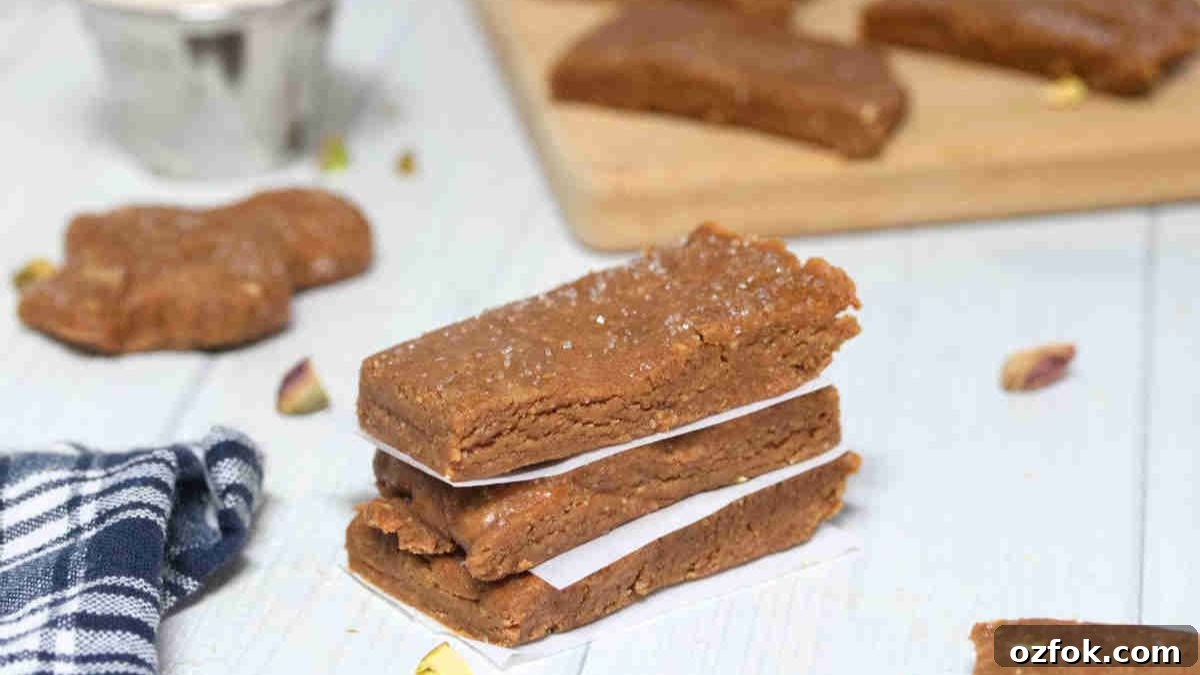 5-Minute Gingerbread Protein Bars Recipe for Quick Snacks 13 Three gingerbread protein bars stacked with parchment paper between them and pistachios around them.
