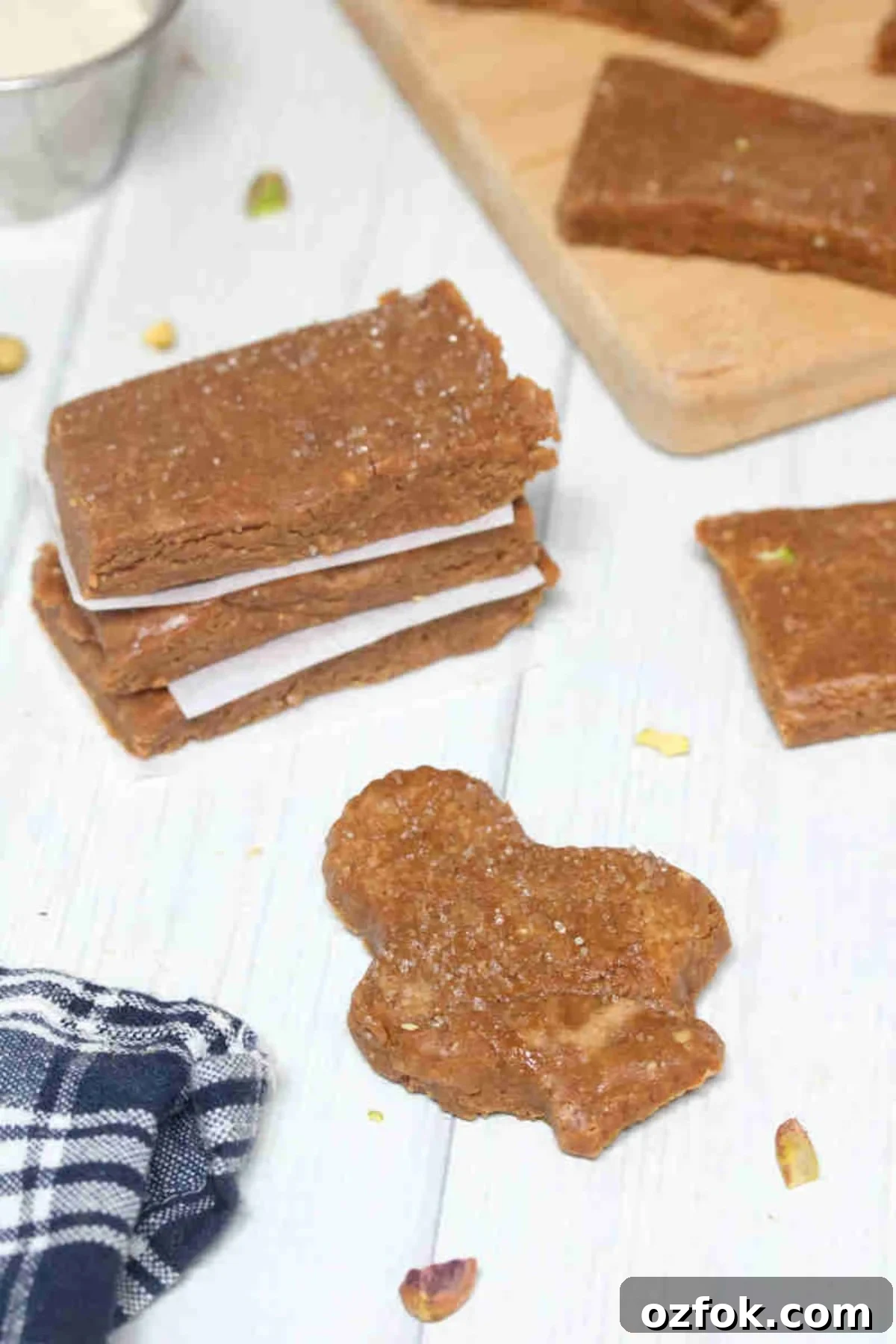 5-Minute Gingerbread Protein Bars Recipe for Quick Snacks 7 Gingerbread protein bars in a gingerbread shape and more stacked with pistachios and a linen around them.