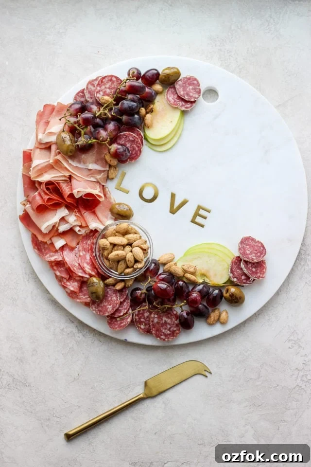 Charcuterie Board A large round marble stone with a variety of deli meats, fresh fruit, and nuts.