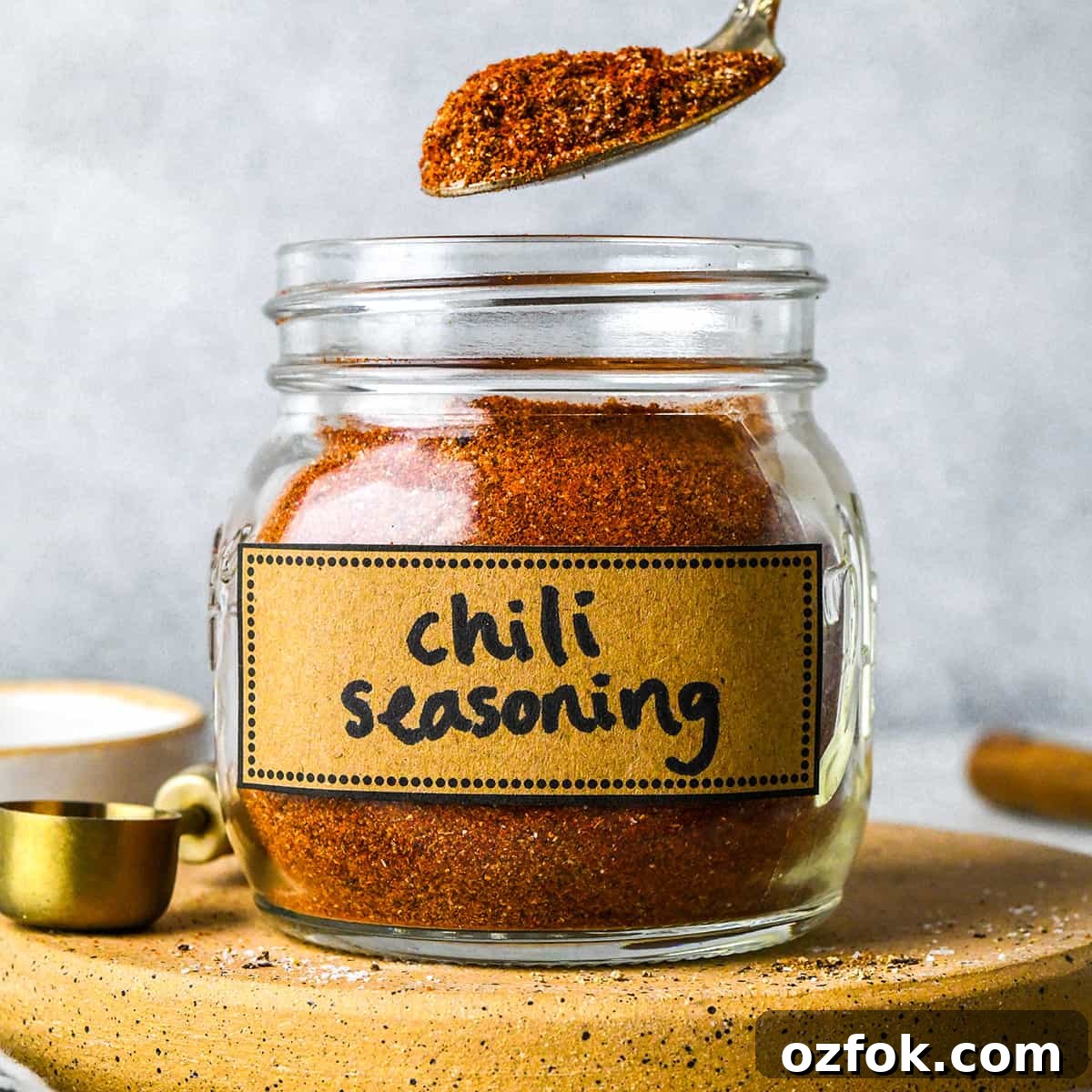 Homemade Chili Seasoning Blend for Bold, Authentic Flavor 2 a spoon taking a scoop of Homemade Chili Seasoning Recipe out of a jar labeled "chili seasoning"