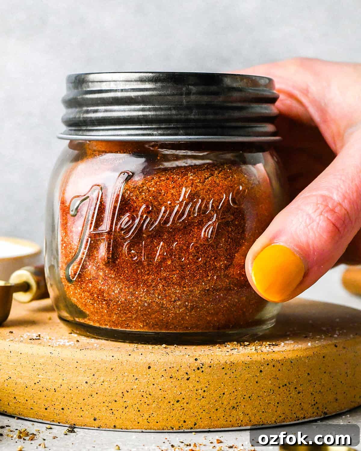 Homemade Chili Seasoning Blend for Bold, Authentic Flavor 8 a hand holding a glass jar with chili seasoning ingredients inside and a lid on after shaking to mix the ingredients