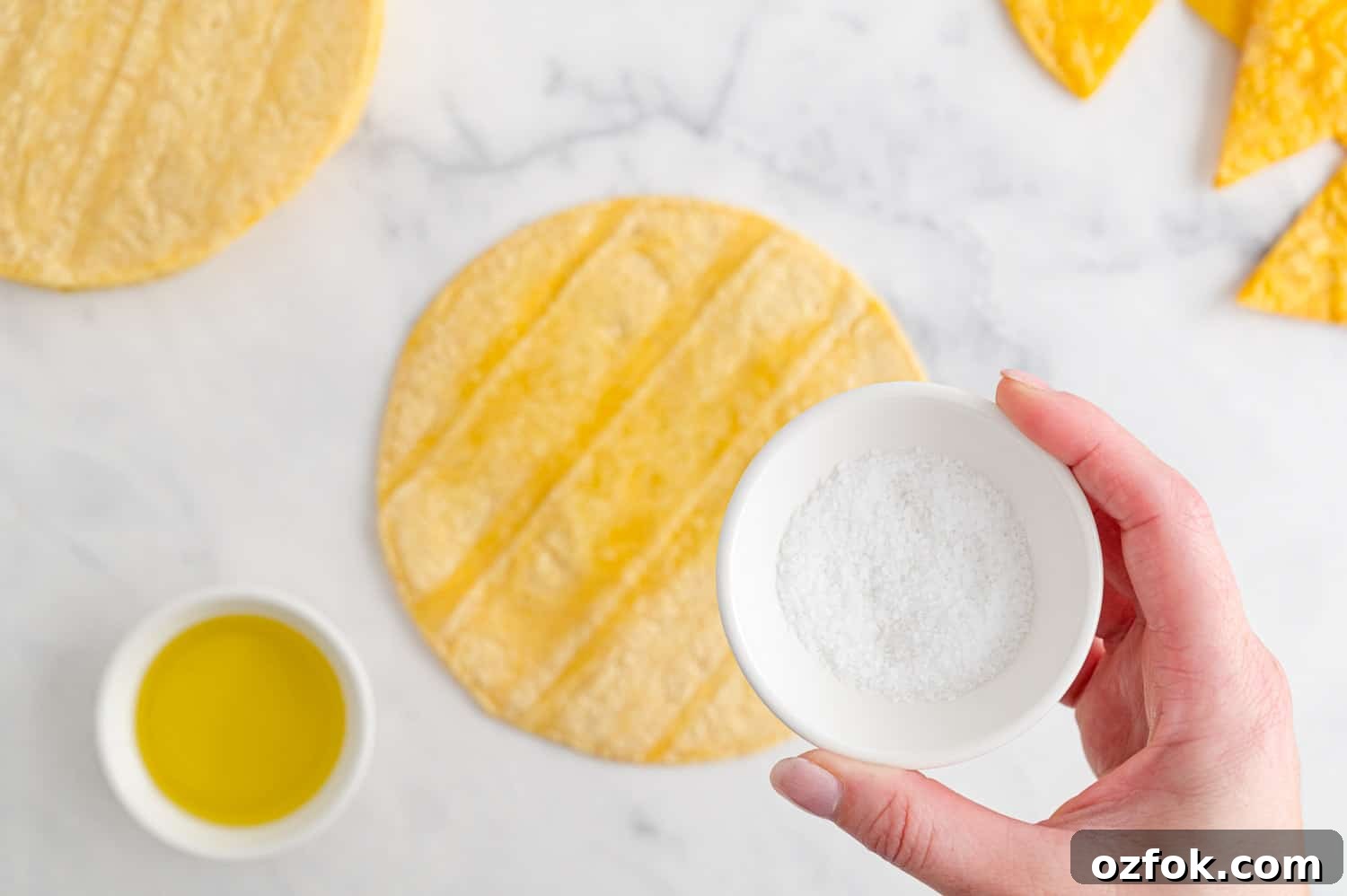 Crispy Air Fryer Tortilla Chips Recipe for Perfect Crunch 7 Salt being sprinkled on a corn tortilla.
