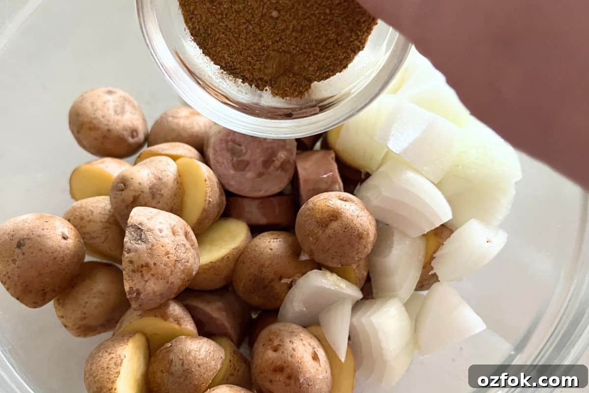 Smoked Sausage and Potatoes Skillet Recipe for Dinner 5 Potatoes, sausage, and onion in a bowl with olive oil.