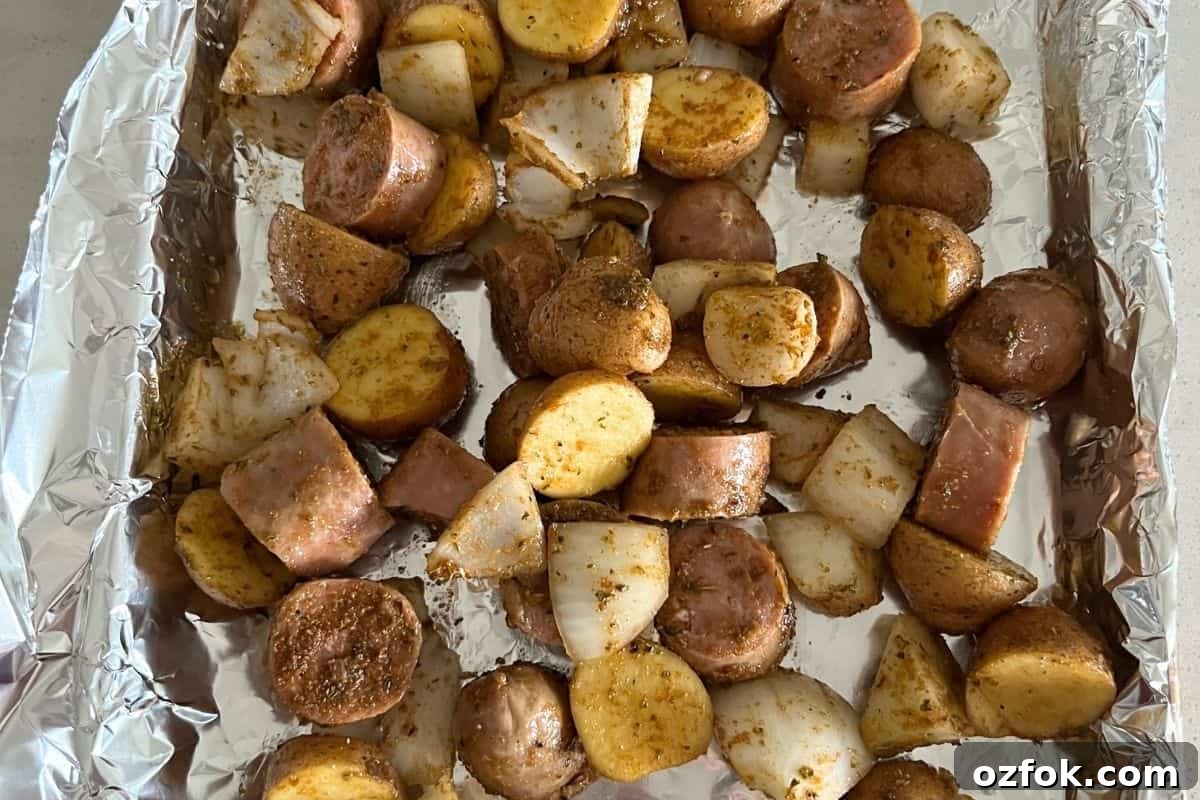 Smoked Sausage and Potatoes Skillet Recipe for Dinner 6 Seasoned sausage and potatoes on a baking tray lined with foil.