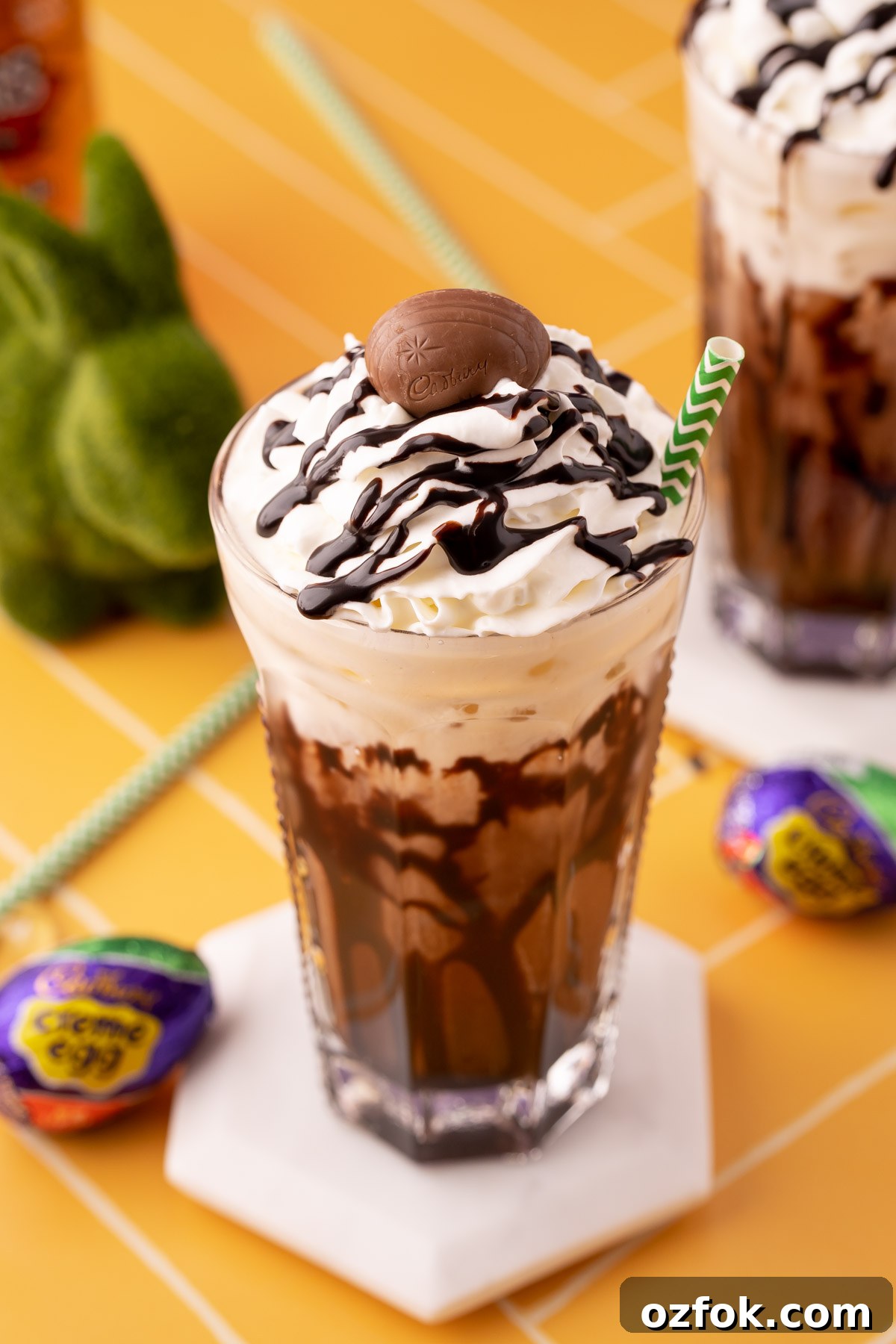 Crème Egg Dirty Soda Recipe: Candy-Inspired Creamy Fizzy Drink 3 A Cadbury Creme Egg flavored dirty soda on a white coaster on a yellow table.