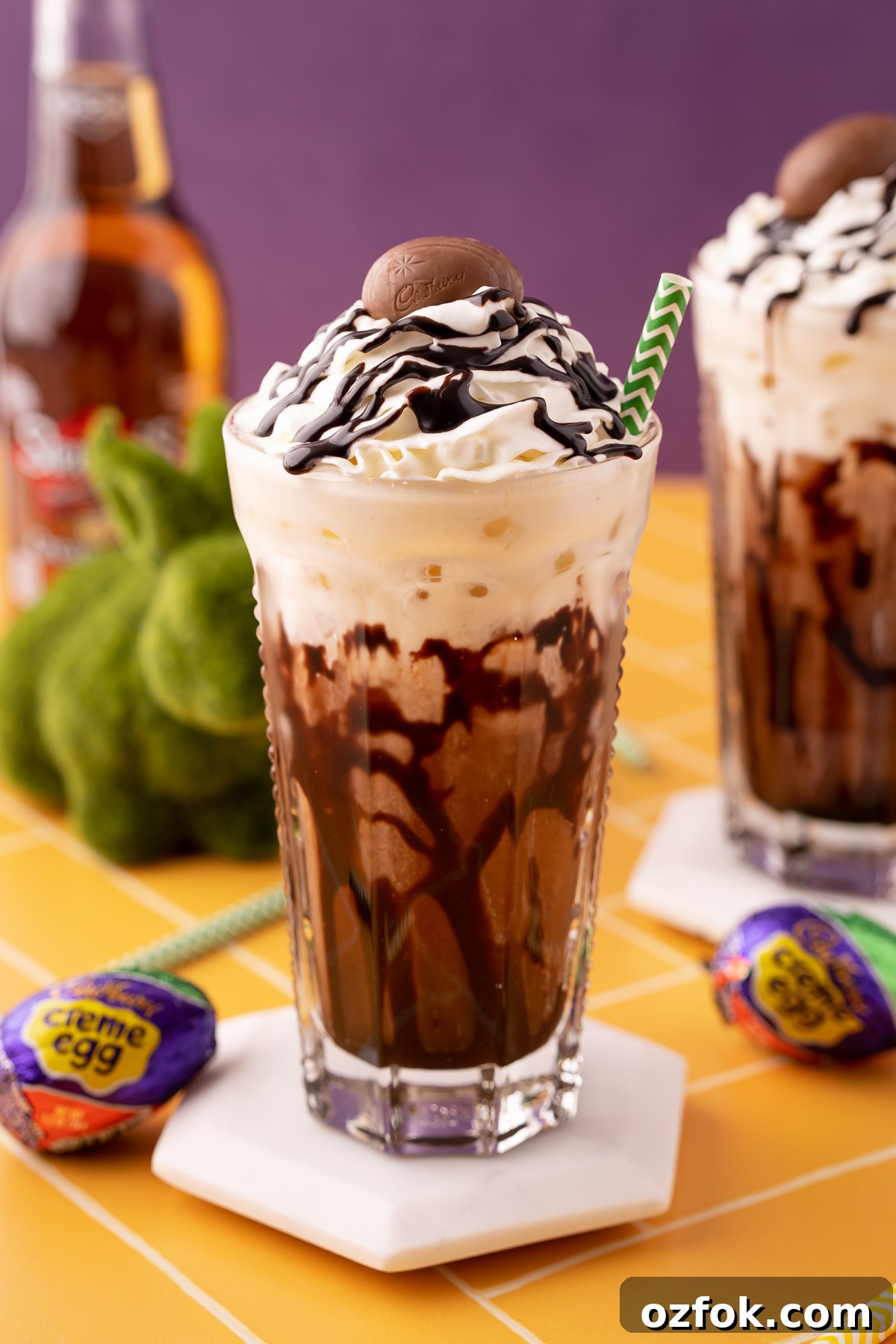 Crème Egg Dirty Soda Recipe: Candy-Inspired Creamy Fizzy Drink 6 A Cadbury Creme Egg flavored dirty soda on a white coaster on a yellow table.
