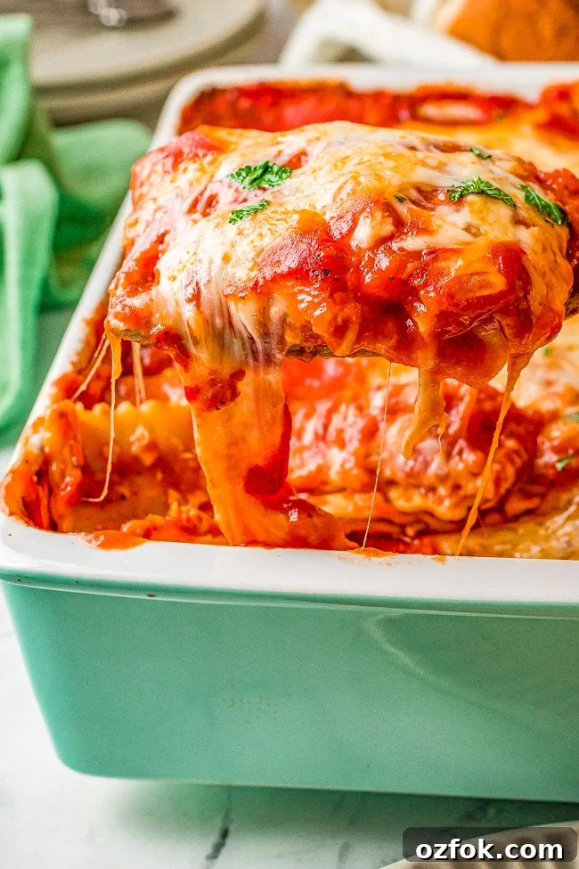 Cheesy Ravioli Lasagna Recipe: Layered Baked Pasta with Marinara 2 A serving of cheese ravioli lasagna being lifted from a baking dish.