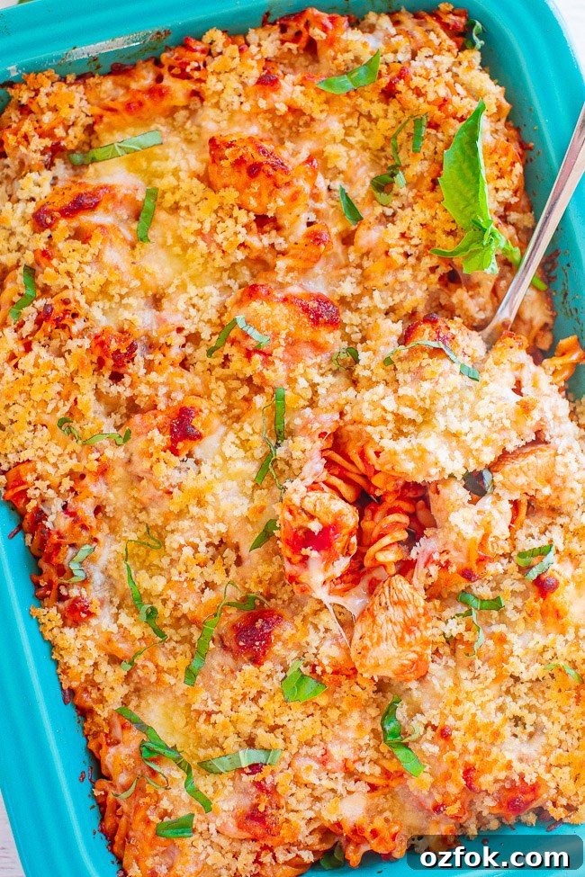 Cheesy Ravioli Lasagna Recipe: Layered Baked Pasta with Marinara 17 Chicken parmesan pasta bake in a casserole dish with a spoon sticking out.