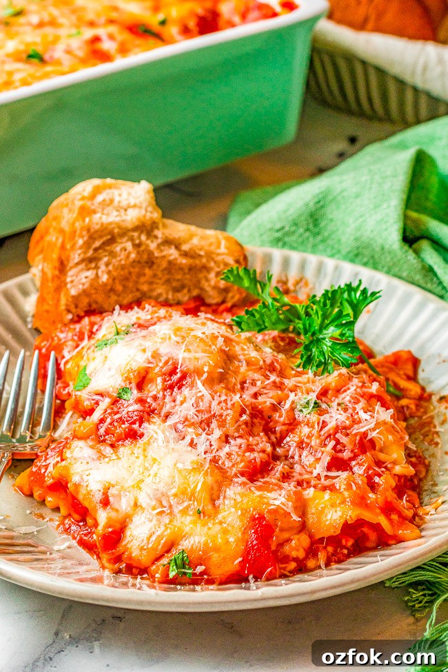Cheesy Ravioli Lasagna Recipe: Layered Baked Pasta with Marinara 5 A plate of cheesy baked lasagna served with a slice of bread and garnished with parsley.