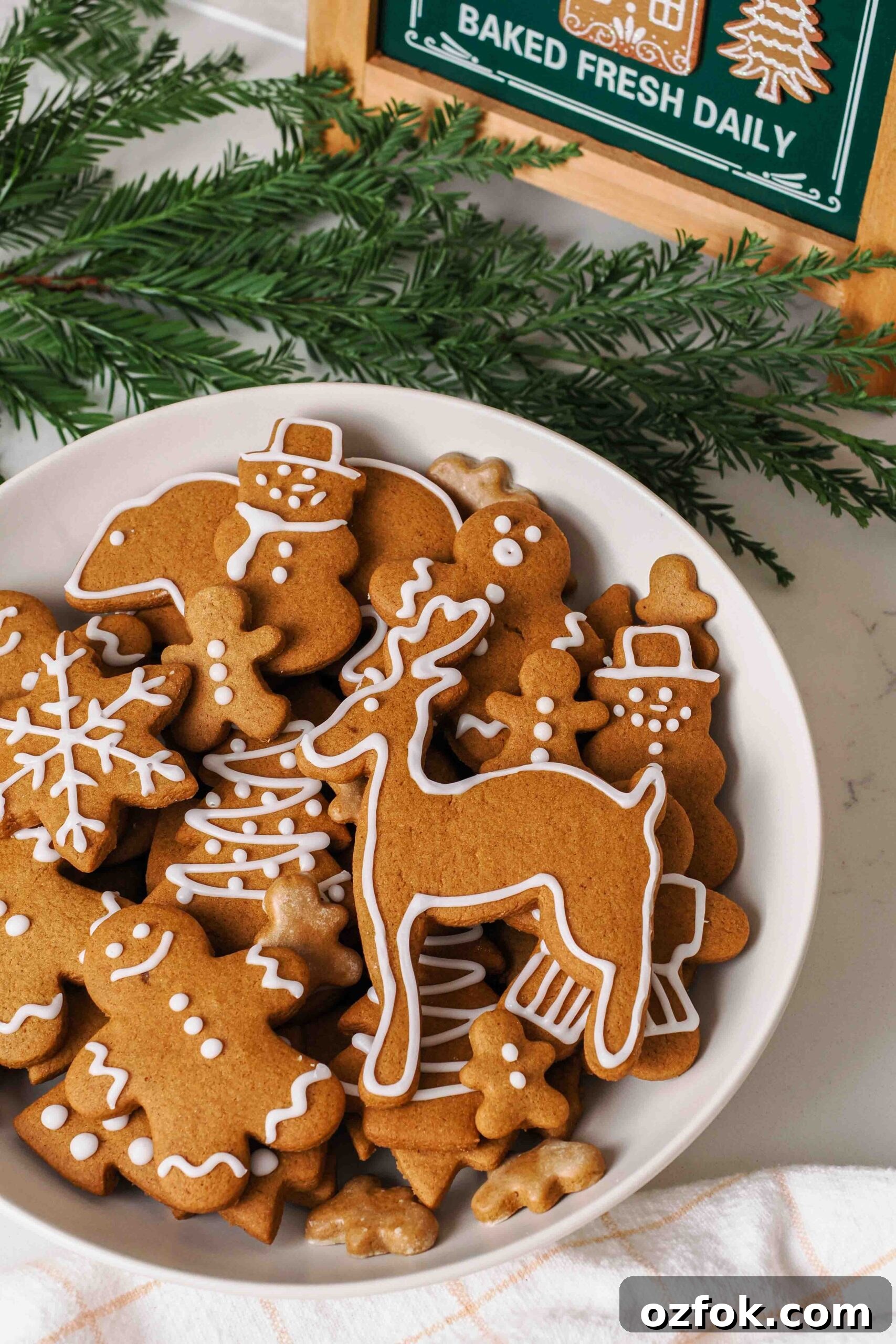 A platter of gingerbread cookies by a pine bough.