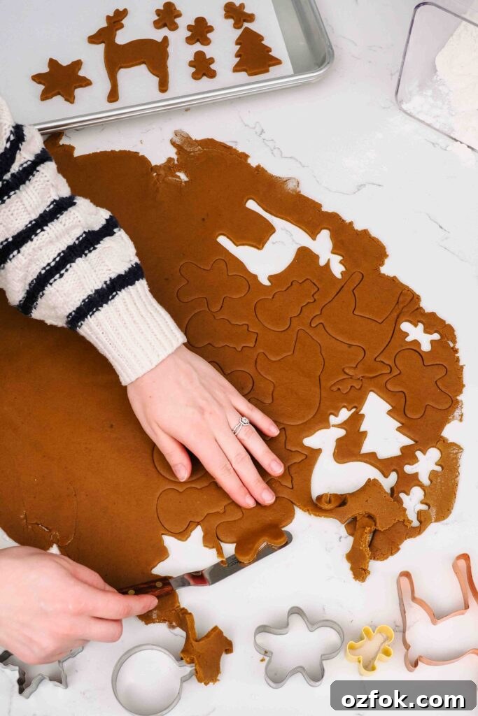 Carefully picking up a dough cutout of a gingerbread man.