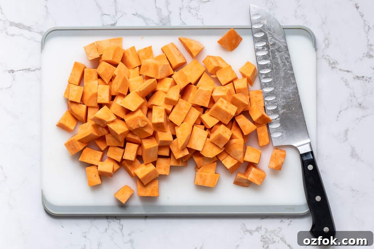 Crispy Tofu Buddha Bowl with Sesame Ginger Dressing 5 chopped sweet potatoes on cutting board with knife.