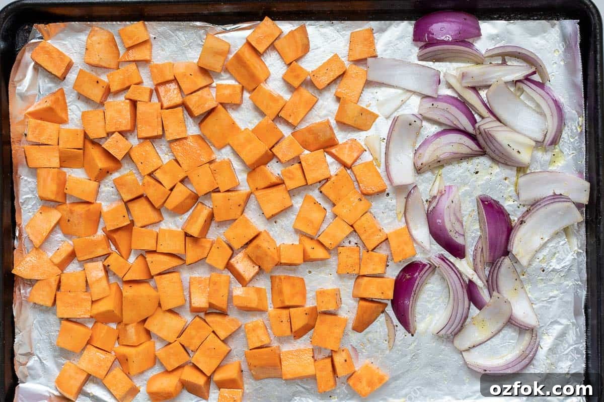 Crispy Tofu Buddha Bowl with Sesame Ginger Dressing 6 cubed sweet potatoes and red onion wedges on sheet pan.