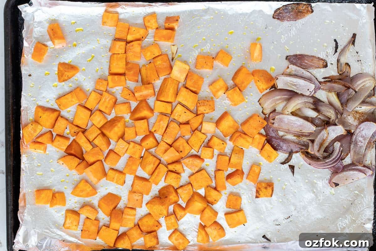 Crispy Tofu Buddha Bowl with Sesame Ginger Dressing 7 roasted sweet potato cubes and red onions on sheet pan.
