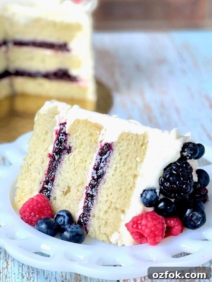 slice of vanilla cake made with the reverse creaming method with berry filling and a bowl of mixed berry cake filling