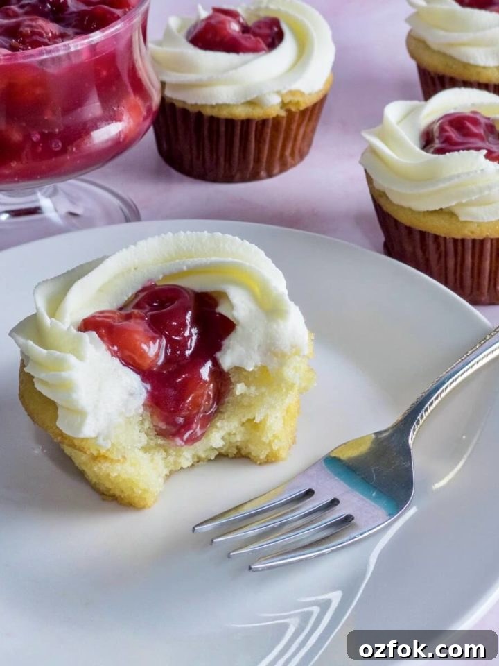 A closeup of a vanilla cupcake filled with cherry filling