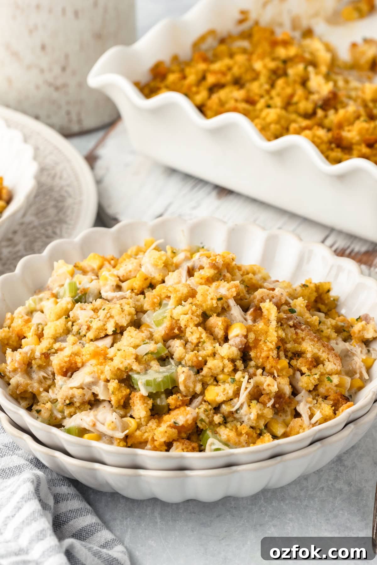 A white scalloped bowl filled with chicken and cornbread stuffing.