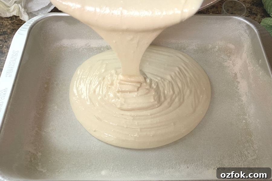 Patriotic Red White & Blue Poke Cake Recipe for 4th of July 5 white cake batter being poured into a greased and floured pan