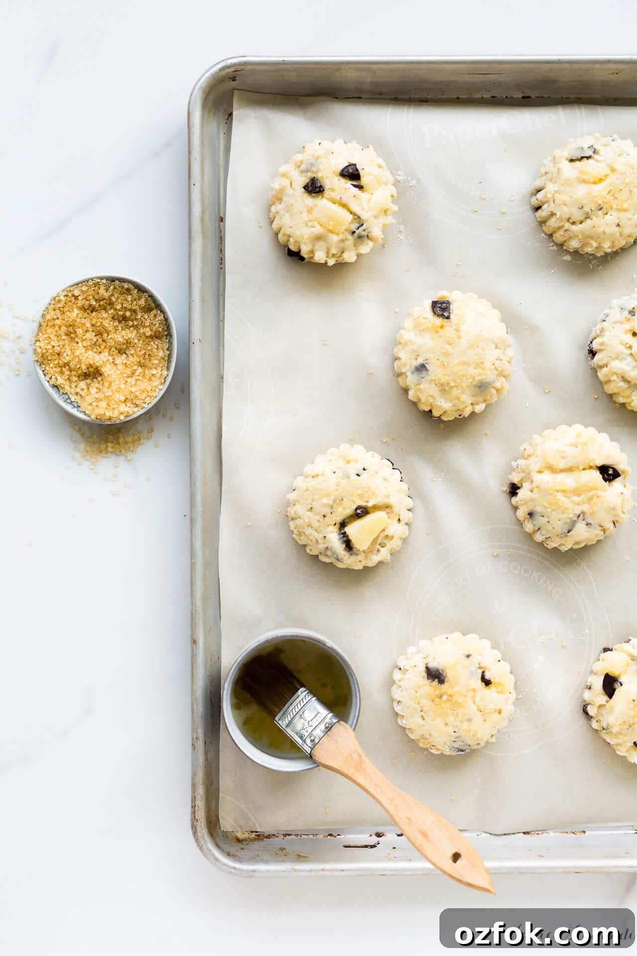 Chocolate Pear Scones: Flaky Scones with Poached Pear Pieces 3 Pear chocolate scones brushed with butter and sprinkled with turbinado before baking on a parchment-lined sheet pan