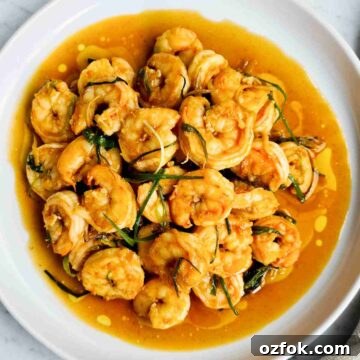 Chinese-Style Prawn Stir-Fry with Ginger and Spring Onions 14 Stir fried peeled prawns on a white round plate with sauce