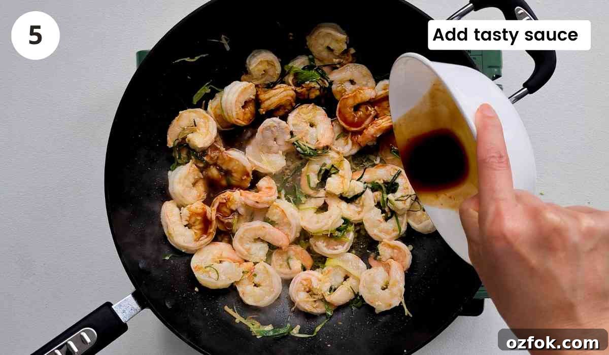 Chinese-Style Prawn Stir-Fry with Ginger and Spring Onions 9 Pre-made Chinese seasoning sauce being poured into the wok with caption