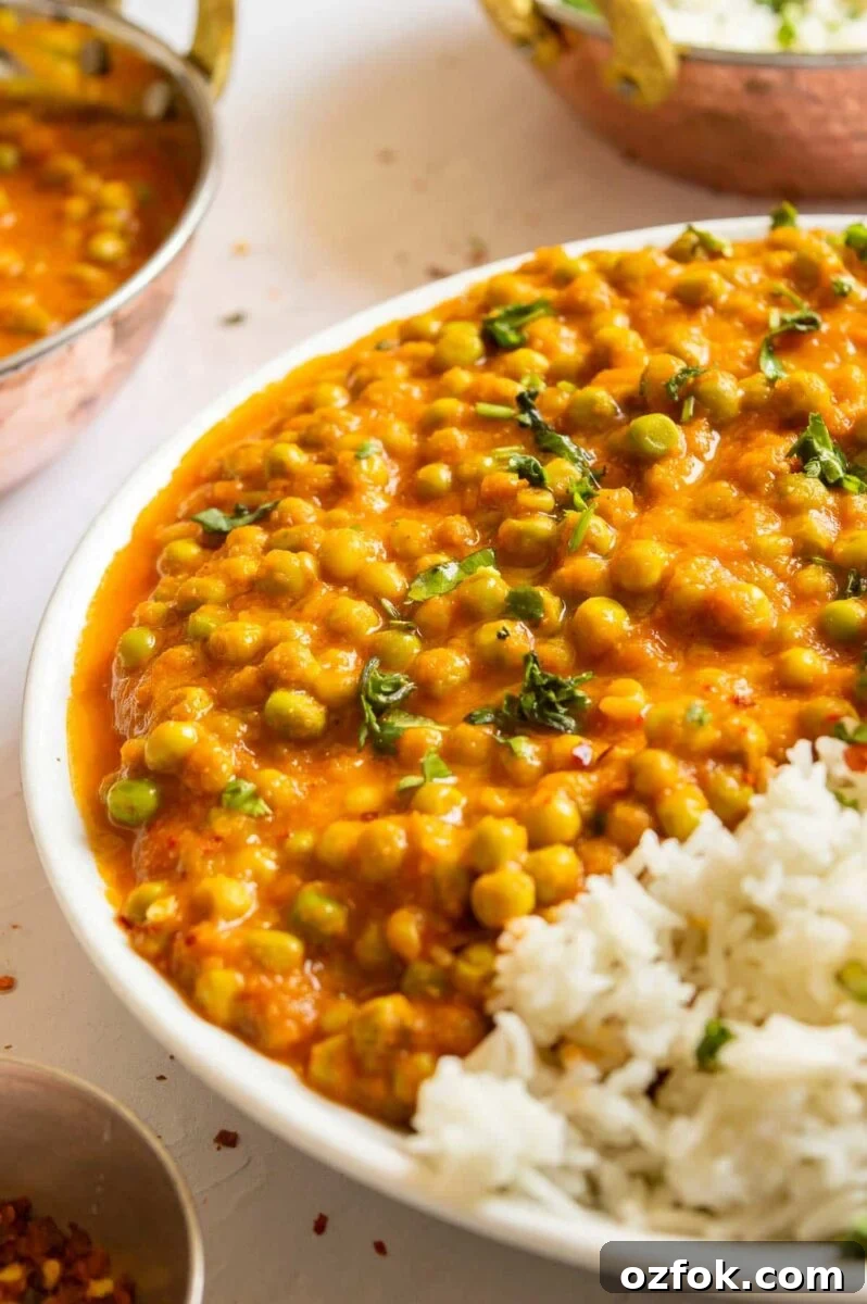 Quick and Flavorful Pea Curry Recipe for Weeknight Meals 2 Front view of a plate with a little white rice and lots of peas in orange sauce.